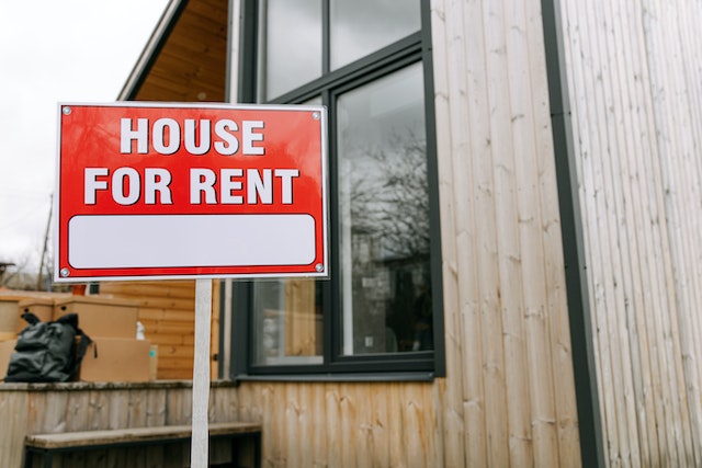 for rent sign in front of a house with wooden siding 